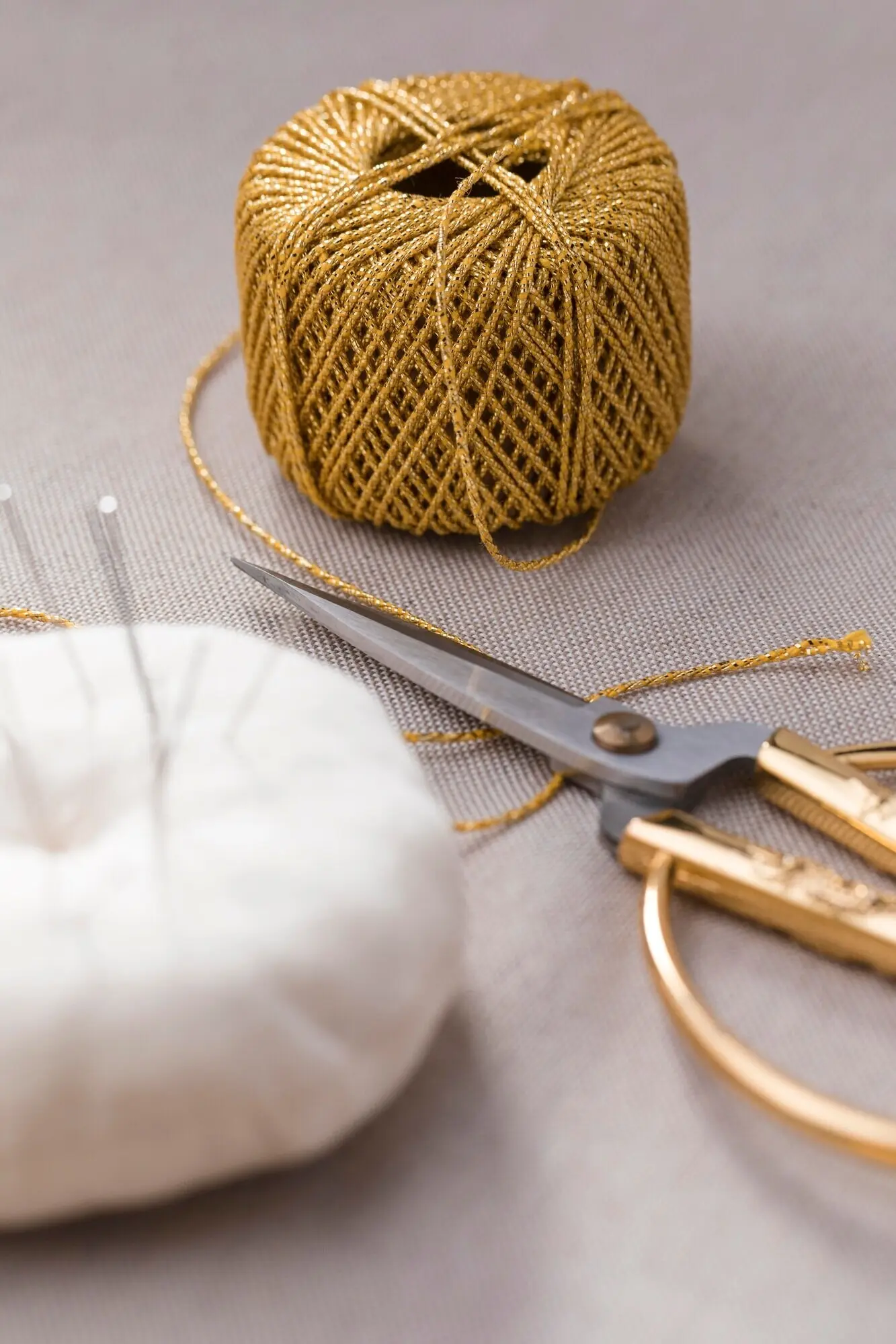 Aufnahme aus der Vogelperspektive von Garn mit Schere und Nähnadeln.